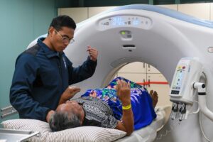 Tecnólogo médico prepara a un paciente para una tomografía