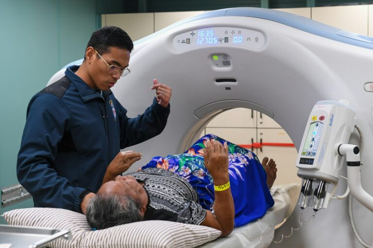 Tecnólogo médico prepara a un paciente para una tomografía